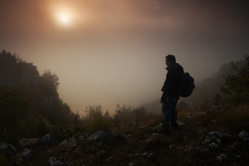 Man standing above the misty canyon early in the morning
