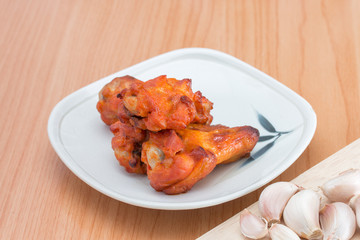 Chicken wings in dish on wooden table.