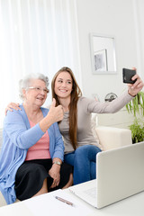 elderly woman making selfie with her young granddaughter at home