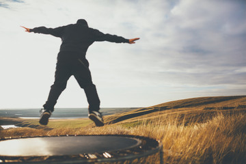 Out of focus man jumping on trampoline in Iceland. Concept of freedom and loneliness.