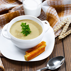 Vegetable soup with parsley and fried bread on a wooden table.