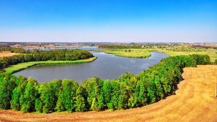Rural, rustic landscape with river and wheat fields in summer da