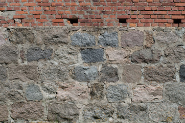 Wall made of irregular granite stones with red brick
