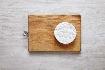Camembert on side of the chopping wooden board on brushed white