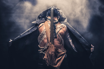 man in the gas mask in the hood, on the black background surrounded by smoke, , survival soldier after apocalypse. - obrazy, fototapety, plakaty