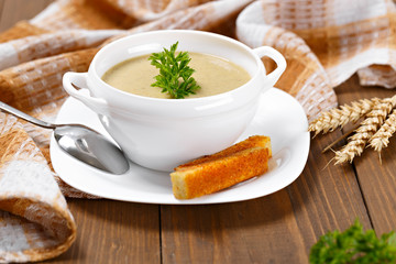 A cup of vegetable soup with parsley and fried bread on a dining