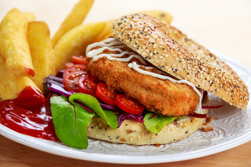 Home made Chicken burger with fried potatoes on old wooden table