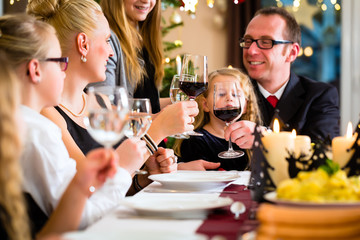 Mutter, Vater, Kinder feiern Weihnachten, essen traditionell Wiener Würstchen und Kartoffelsalat