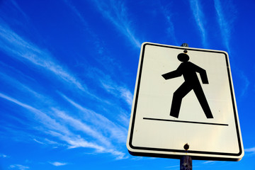 white pedestrian walking sign in the blue sky background