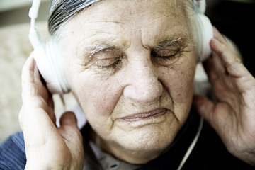 Seniorin mit Kopfhörer und Smartphone hört Musik