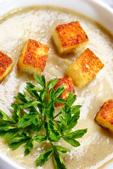 Vegetable soup with pieces of toasted bread and parsley.