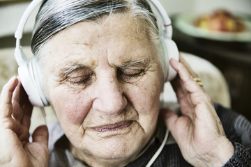 Seniorin mit Kopfhörer und Smartphone hört Musik