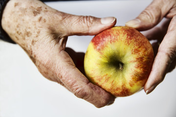 Hände einer Seniorin mit einem Apfel