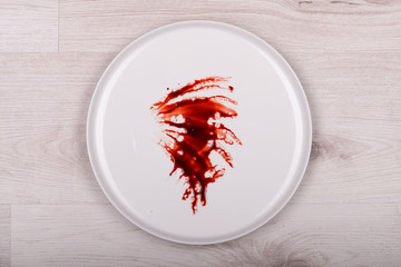 Blood on white plate, wooden background