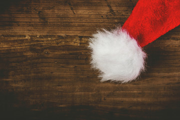 Obraz na płótnie Canvas Retro toned Santa Claus hat on wooden desk