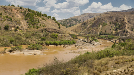Old broken bridge over a muddy river on a landscape in Madagascar, Africa.