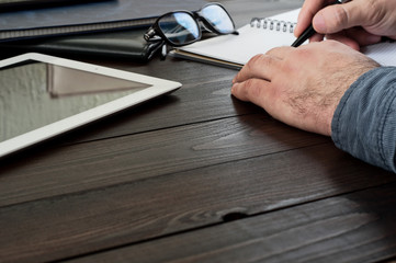 male hands writing in a notebook on the office table