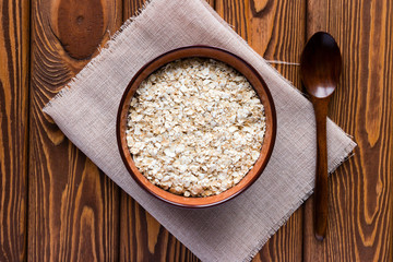 oat flakes in a bowl on a napkin and a wooden spoon