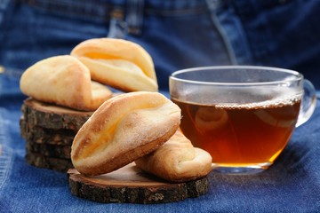Homemade cookies and black tea on wooden stands on deep blue clo