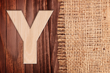 Wooden alphabet letter symbol - Y. On wooden table background with burlap