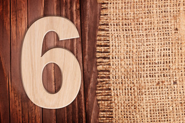 Wooden digit one symbol - 6. On wooden table background with burlap