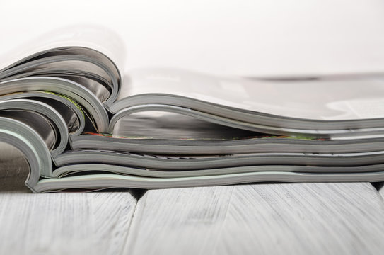 stack of magazines on a white wooden background