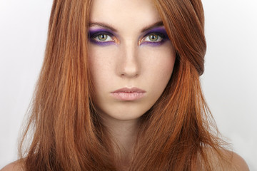 Naklejka premium Closeup portrait of young beautiful redhead woman with gorgeous hair and violet eyes makeup