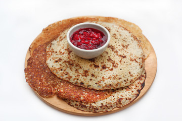 Стопка блинов с брусничным вареньем на деревянной доске