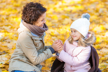 Happy mother sitting on the blanket with her daughter 