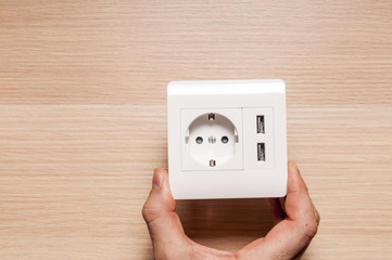 A man hold the electric socket with two usb-charger ports.