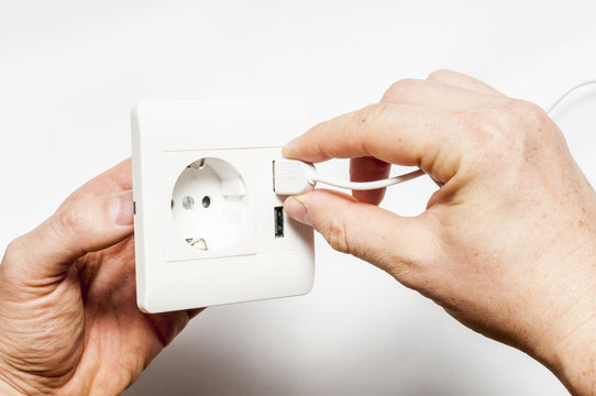 Plug in. A man inserts the usb plug into the usb port of power s