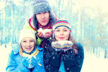 Winter family outdoors. Happy joyful family with kid blowing snow