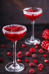 Red alcoholic cocktail with raspberry and pomegranate, in a glass glass on a black background. selective focus.