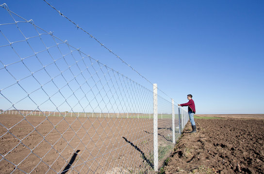 Man holding barbed wire fence