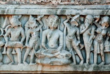 Buddha sitting in the crowd of people on the wall of ancient temple in India