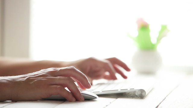 Ladies fingers typing something on the modern keyboard and use a computer mouse