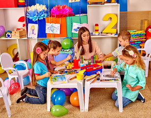 Children with teacher woman painting on paper in  kindergarten