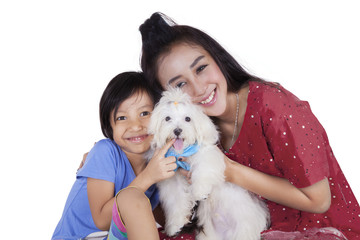 Cute girl and her mother holding dog in studio