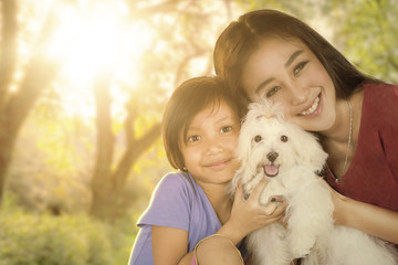 Cute girl and her mother hugging puppy