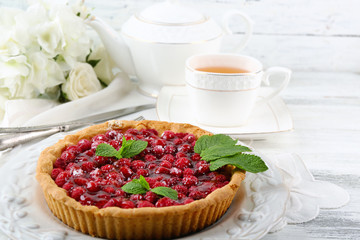 Tart with raspberries and tasty tea, on color  wooden background