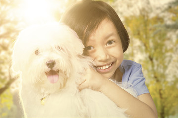 Cute girl holding her puppy at the park