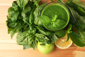 Green healthy juice with fruits and herbs on wooden table close up