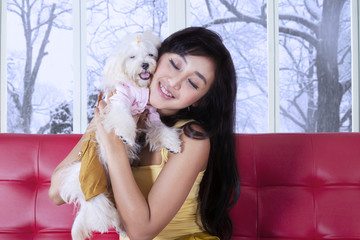 Cute girl hugging her puppy on the sofa