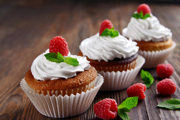 Delicious cupcakes with berries and fresh mint on wooden table close up