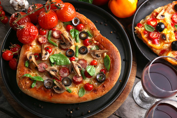 Decorated pizza with vegetables on pan on wooden background