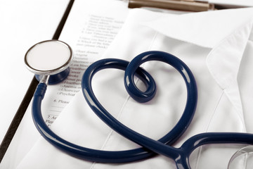 Heart shaped blue stethoscope, medical record and uniform, close up