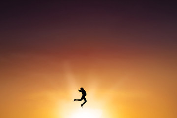 Naklejka na ściany i meble Successful woman leaps on the air at dusk time