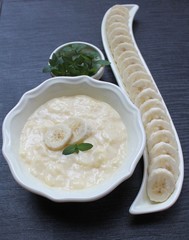 Banana Pudding in a yellow bowl for ice cream on a black table with sliced ​​banana and mint