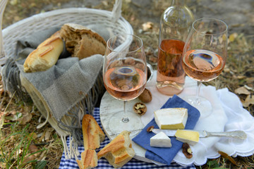 Picnic theme - rose wine, cheese, baguette and nuts outdoors