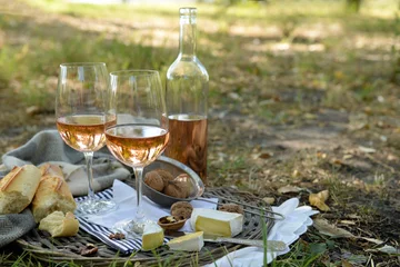 Rucksack Picnic theme - rose wine, cheese, baguette and nuts on wicker tray, outdoors © Africa Studio